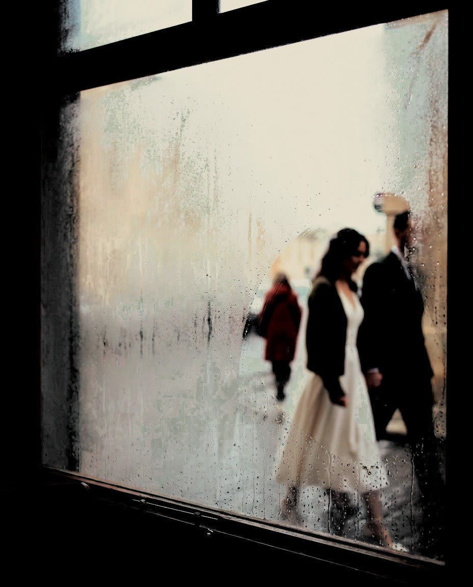 A couple and a figure in red seen through a window clouded with rain, developed in Analog Signature