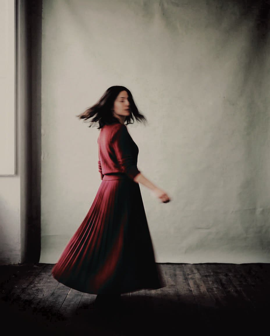 A woman in a red pleated dress turning in a studio, developed in Analog Signature