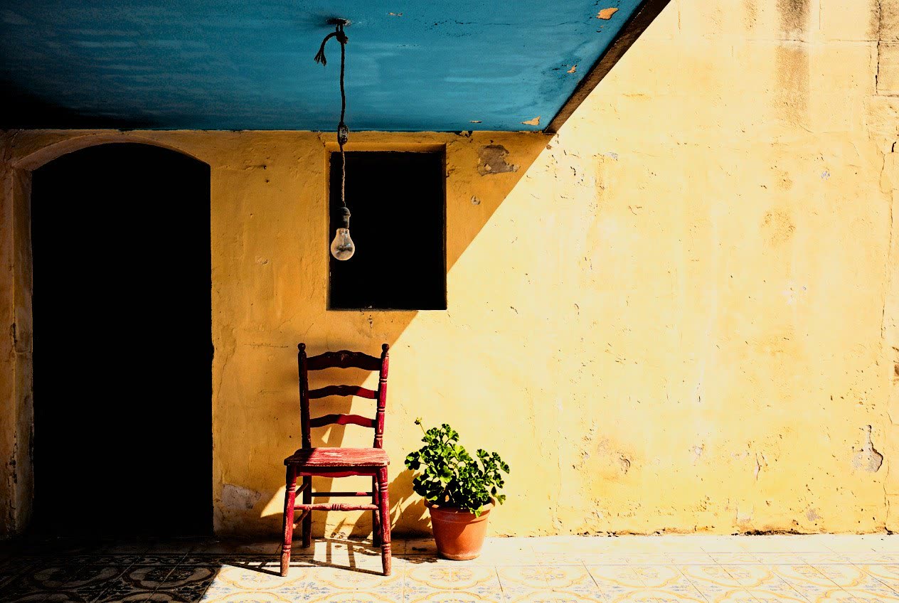 A red chair against a yellow wall under a blue awning on Gozo, developed in Analog Signature